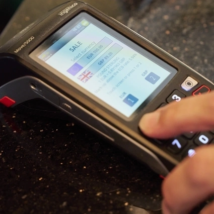 Close-up of a payment terminal showing Dynamic Currency Conversion in progress during a transaction