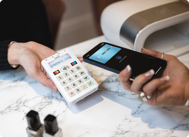 Photo showing cashier showing Elavon mobile terminal for customer to pay